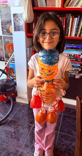 Child proudly presenting a finished sculpture